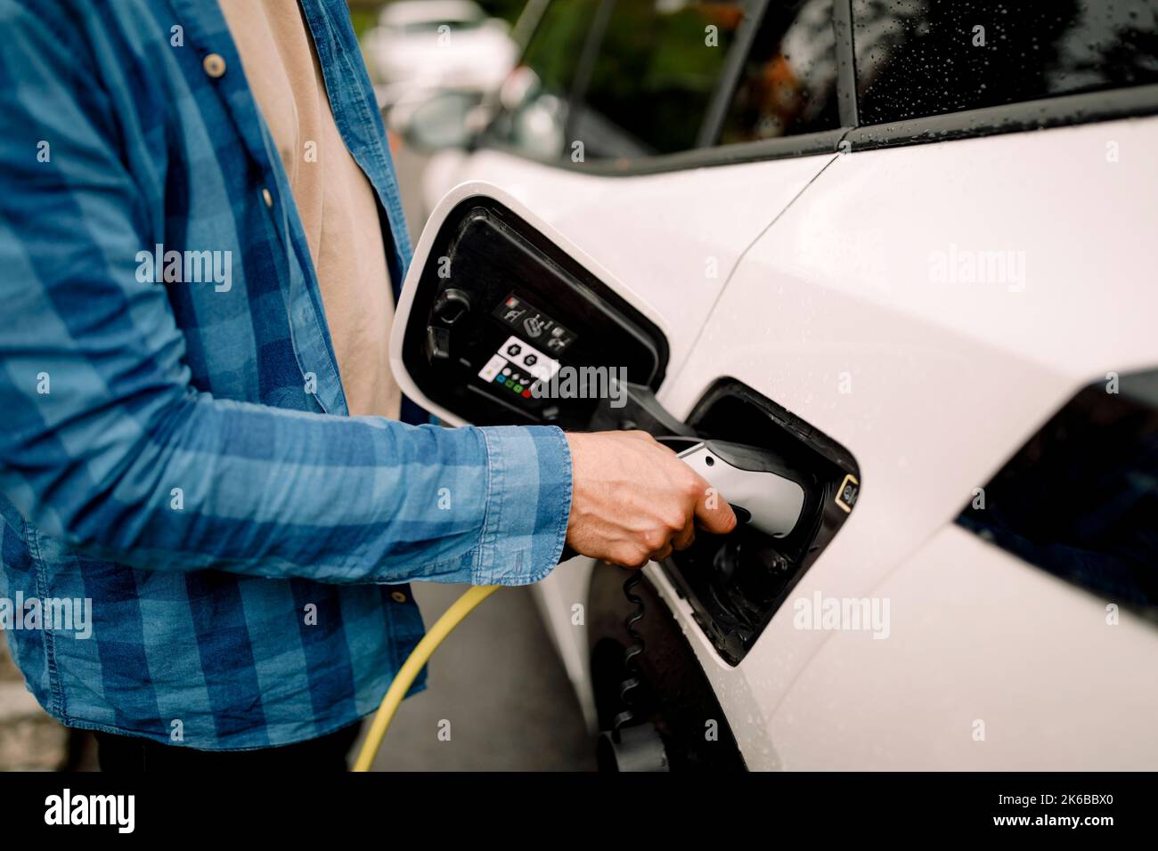 Midsection of man plugging charger in electric car Stock Photo