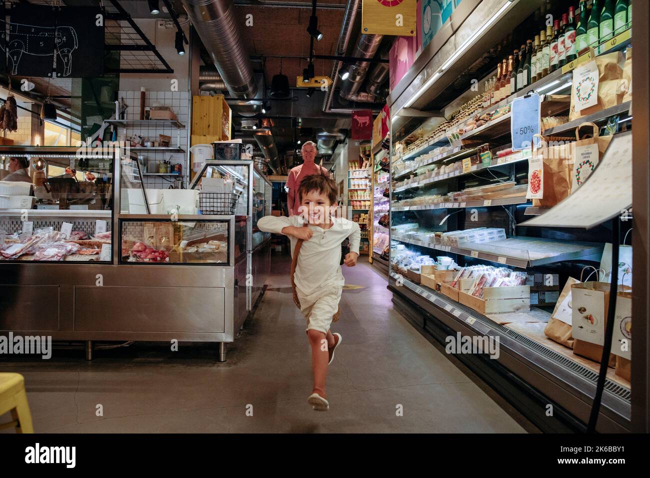 Excited boy running while shopping with grandfather in supermarket Stock Photo