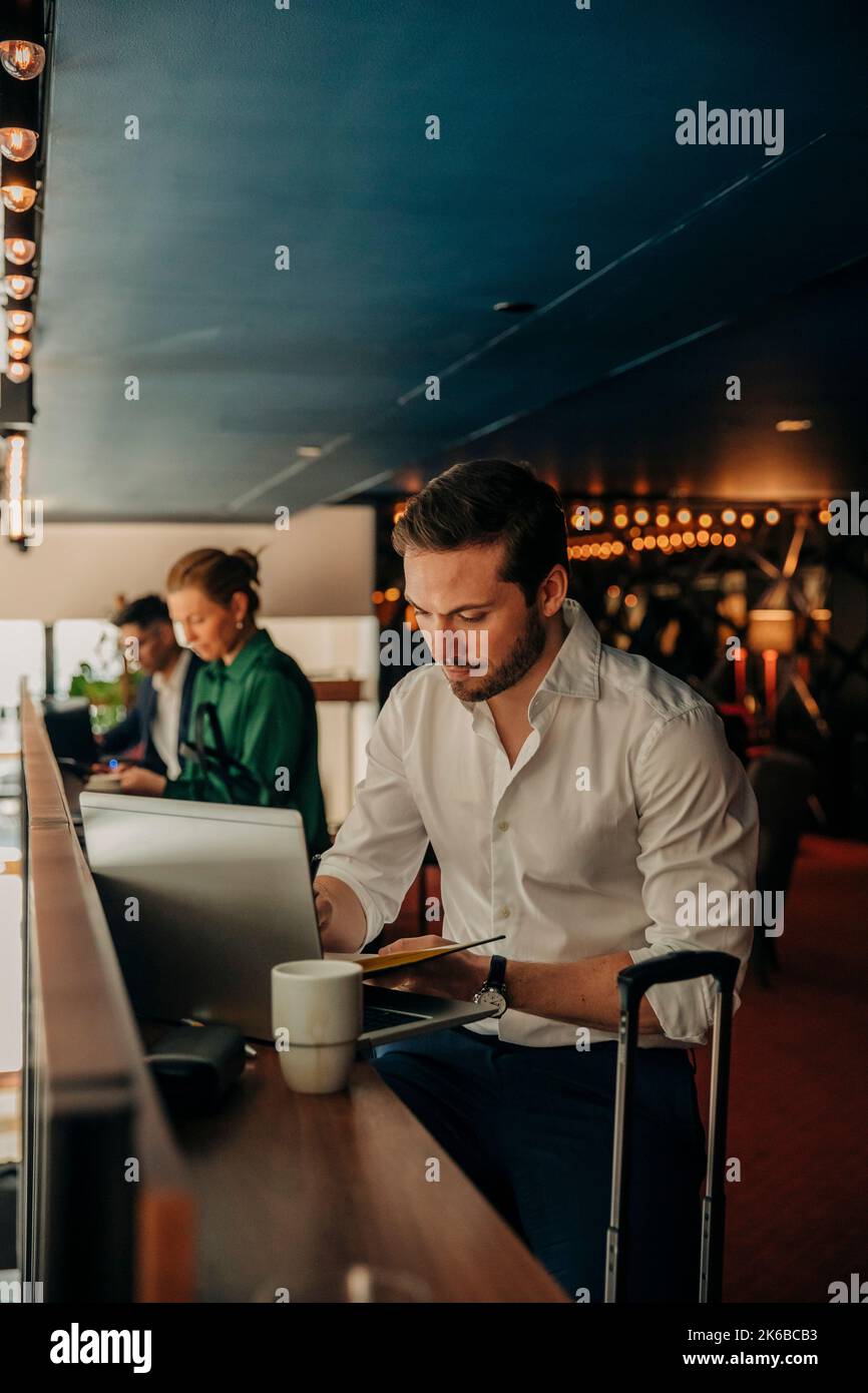 Young businessman using laptop while sitting in hotel Stock Photo