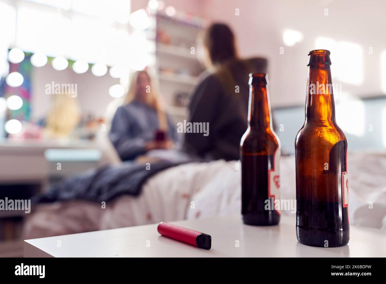 Group Of Teenage Girls In Bedroom With Bottles Of Beer And Vape Pen In Foreground Stock Photo