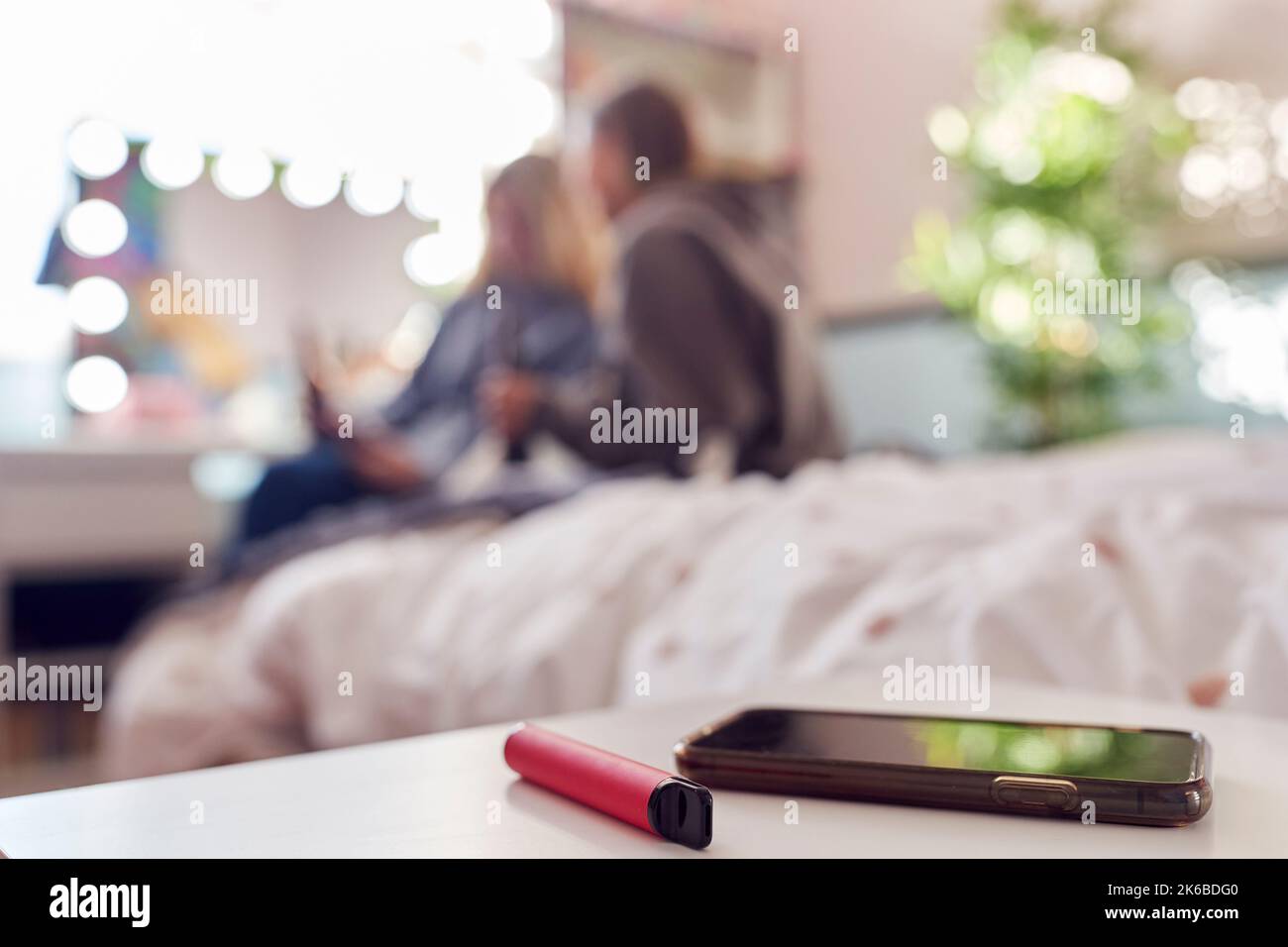 Group Of Teenage Girls In Bedroom With Vape Pen And Mobile Phone In