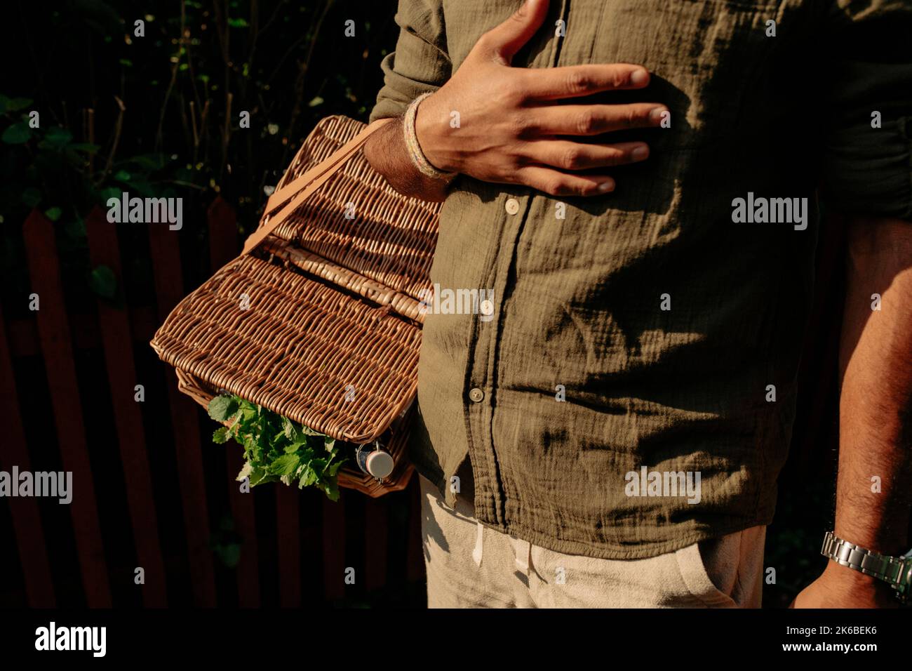 Midsection of man with hand on chest carrying picnic basket Stock Photo