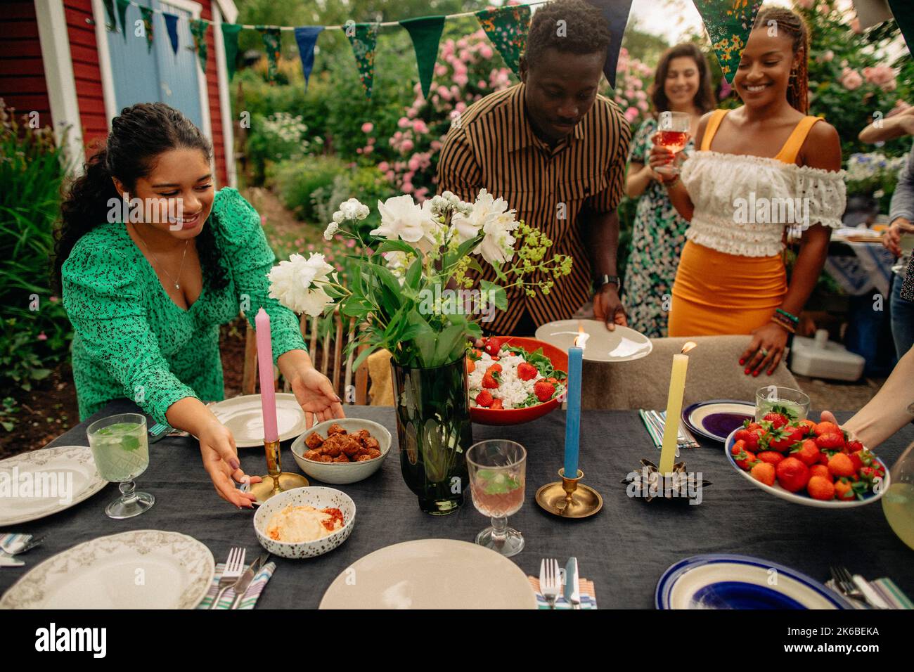 Male and female friends setting up table during garden party Stock Photo