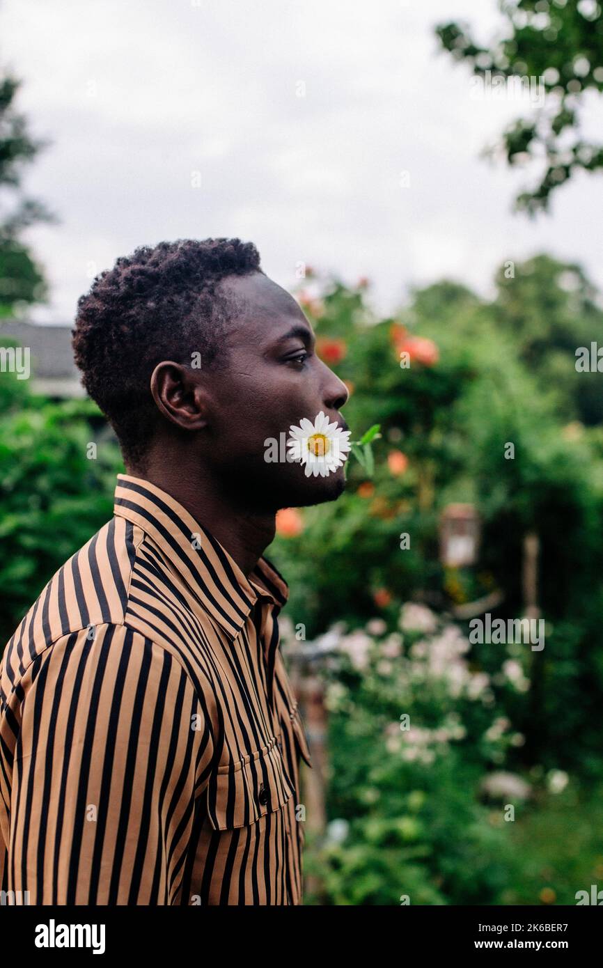 Side view of man holding flower in mouth at garden Stock Photo
