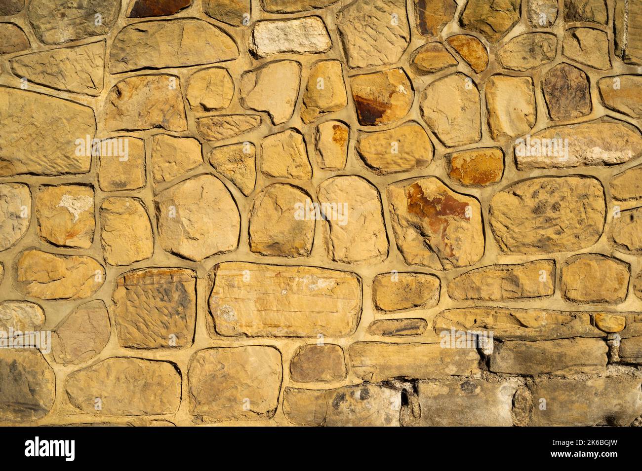 Natural Sandstone Stone Wall Texture Background with Fresh Mortar. Different Sized Uncut Large Stones Stock Photo