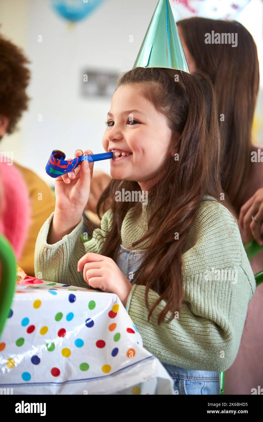 Girl Celebrating Birthday With Party Blower At Party With Parents And ...