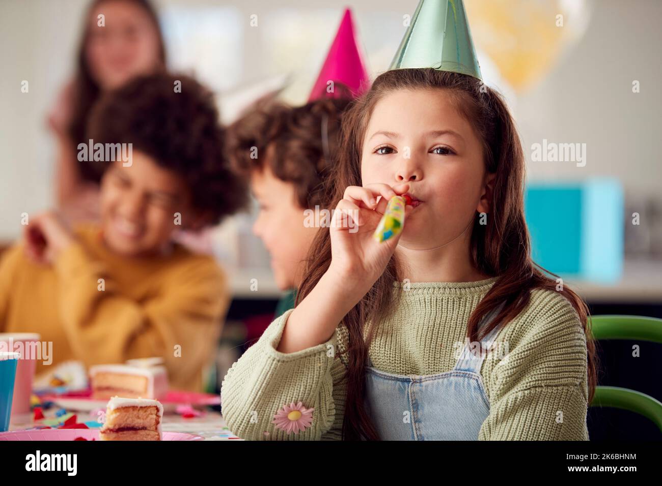 Girl With Birthday Cake And Party Blower At Party With Parents And ...