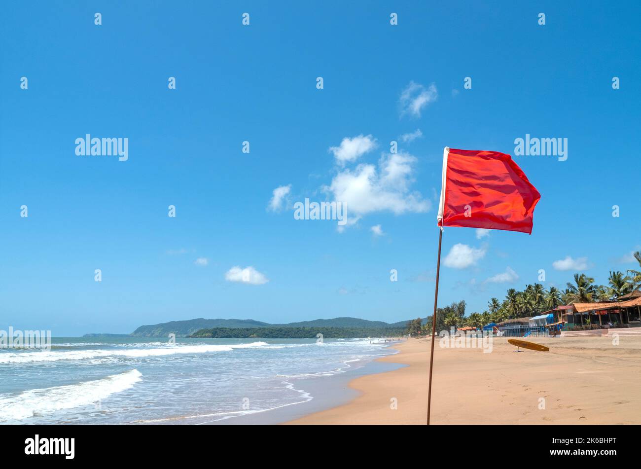 Red flag as warning sign on the beach before storm means no swimming, during windy sunny day Stock Photo