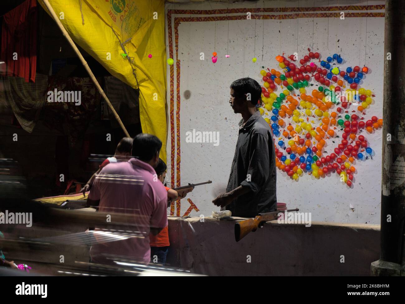 Man teaching his son target shooting with air-gun in balloon shooting stall Stock Photo