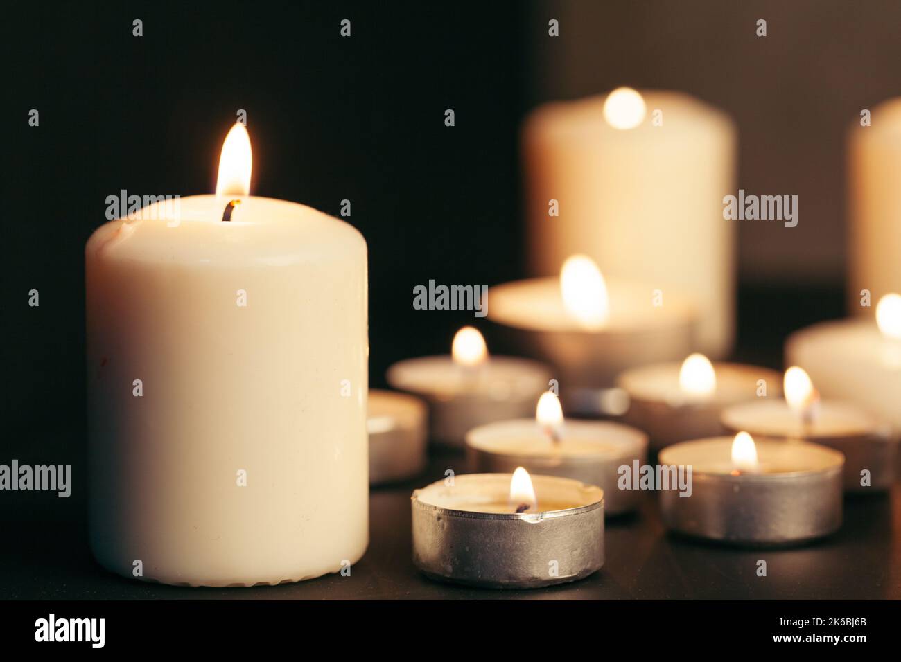 Many candles burning at night. Many candle flames glowing on dark