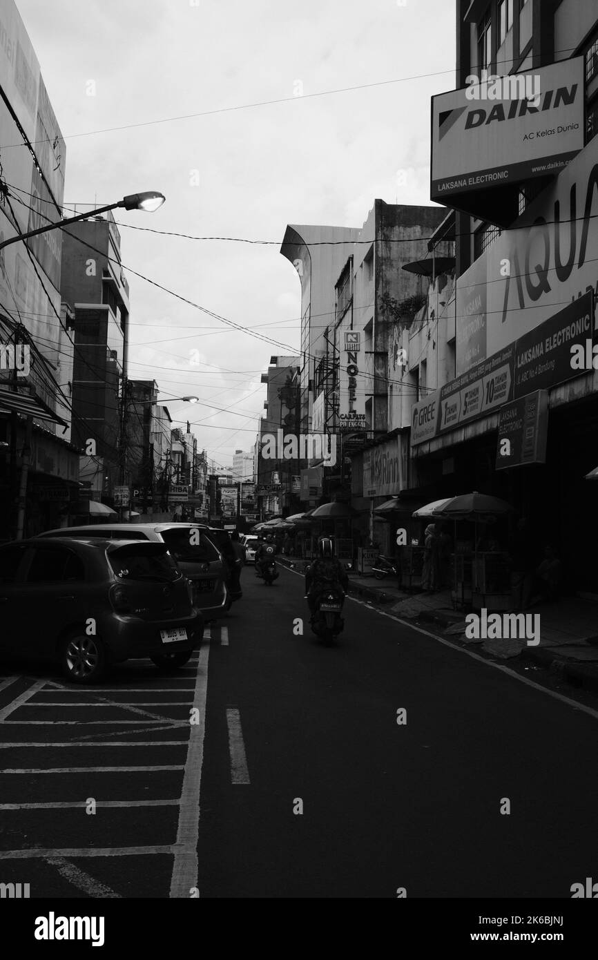 Bandung, West Java, Indonesia - 06 October, 2022 : Monochrome photo, Street scene in an urban area inhabited by shops along the roadside Stock Photo