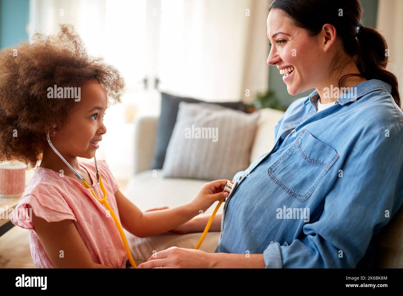 Pregnant Mother With Daughter Listening To Baby Heartbeat Through