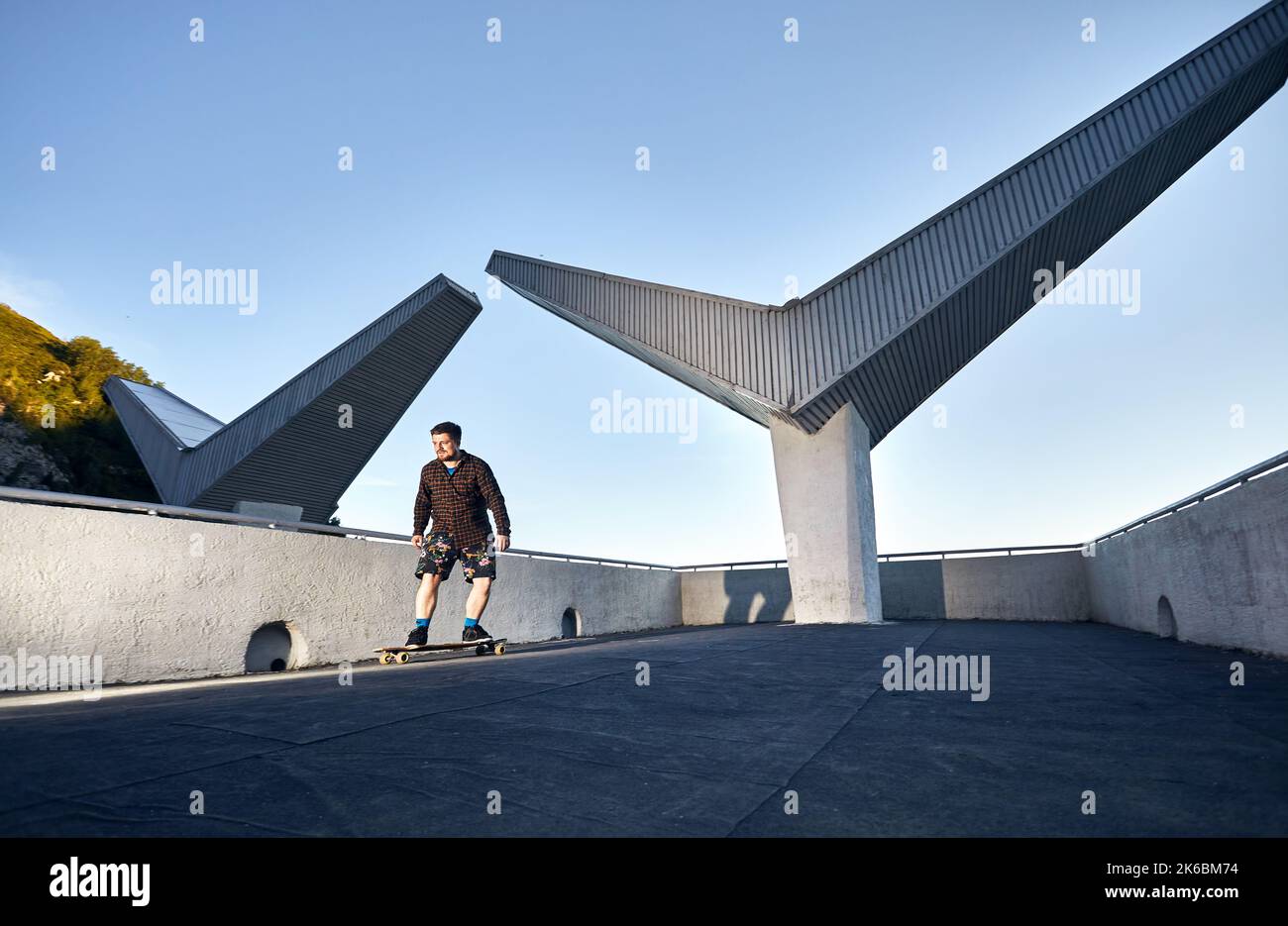 Bearded man Skater ride at his longboard at old soviet building in the mountain in Medeo Dum Almaty, Kazakhstan Stock Photo