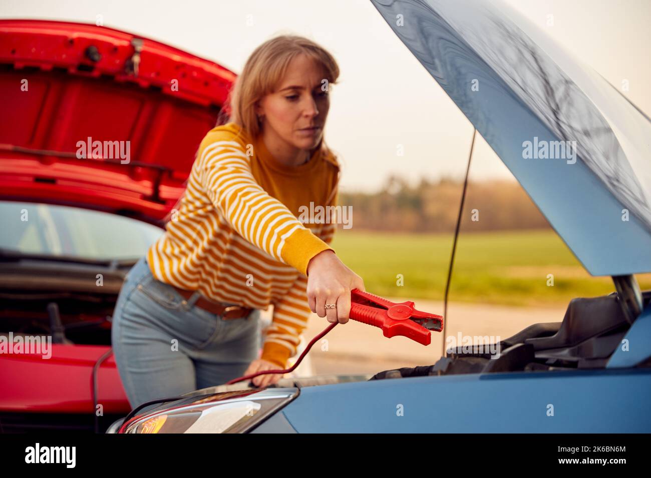Woman Attaching Jumper Cable To Start Car Engine With Flat Battery