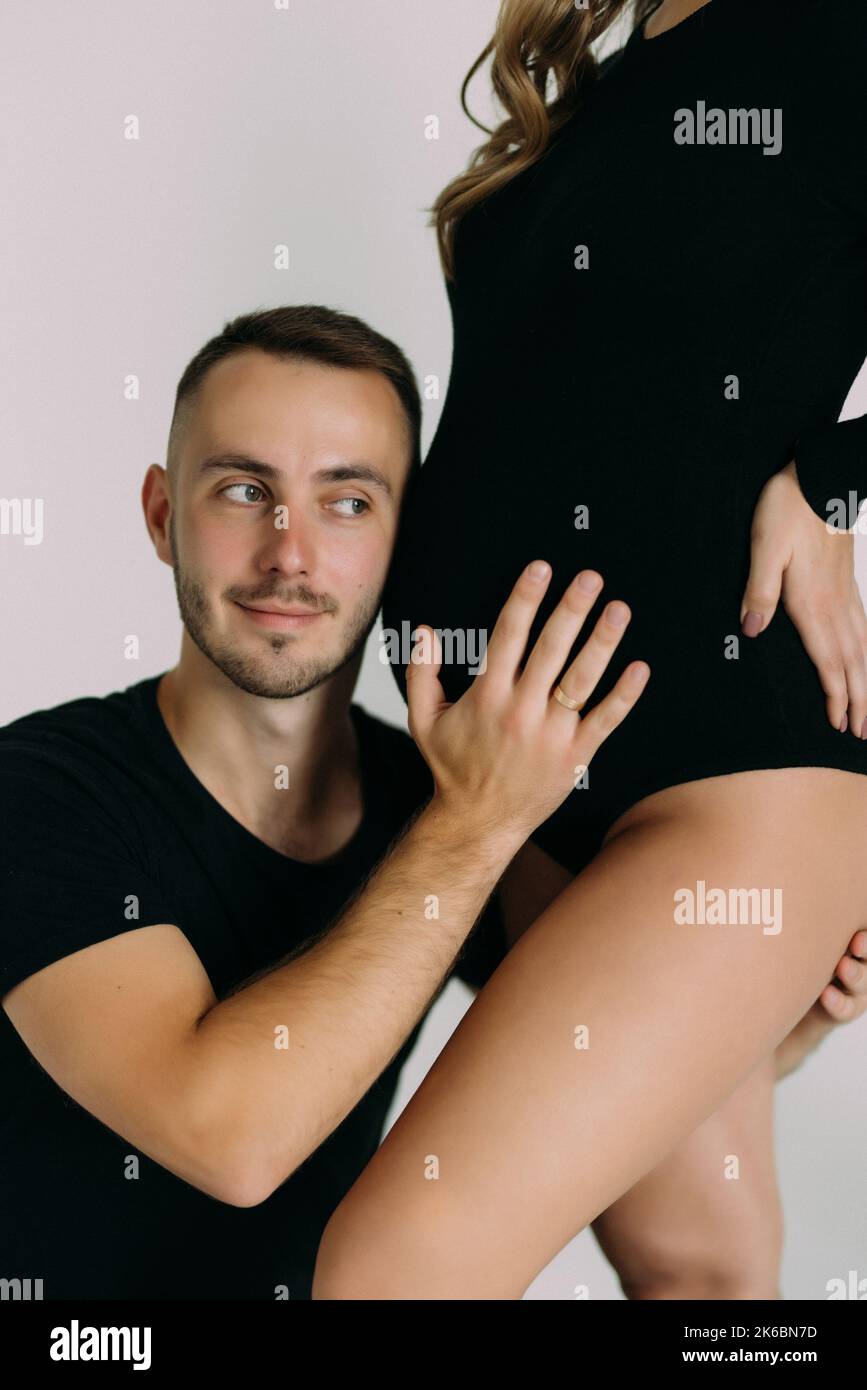 Studio portrait of young parents, pregnant woman, wearing black clothes, man touching the belly on white background Stock Photo