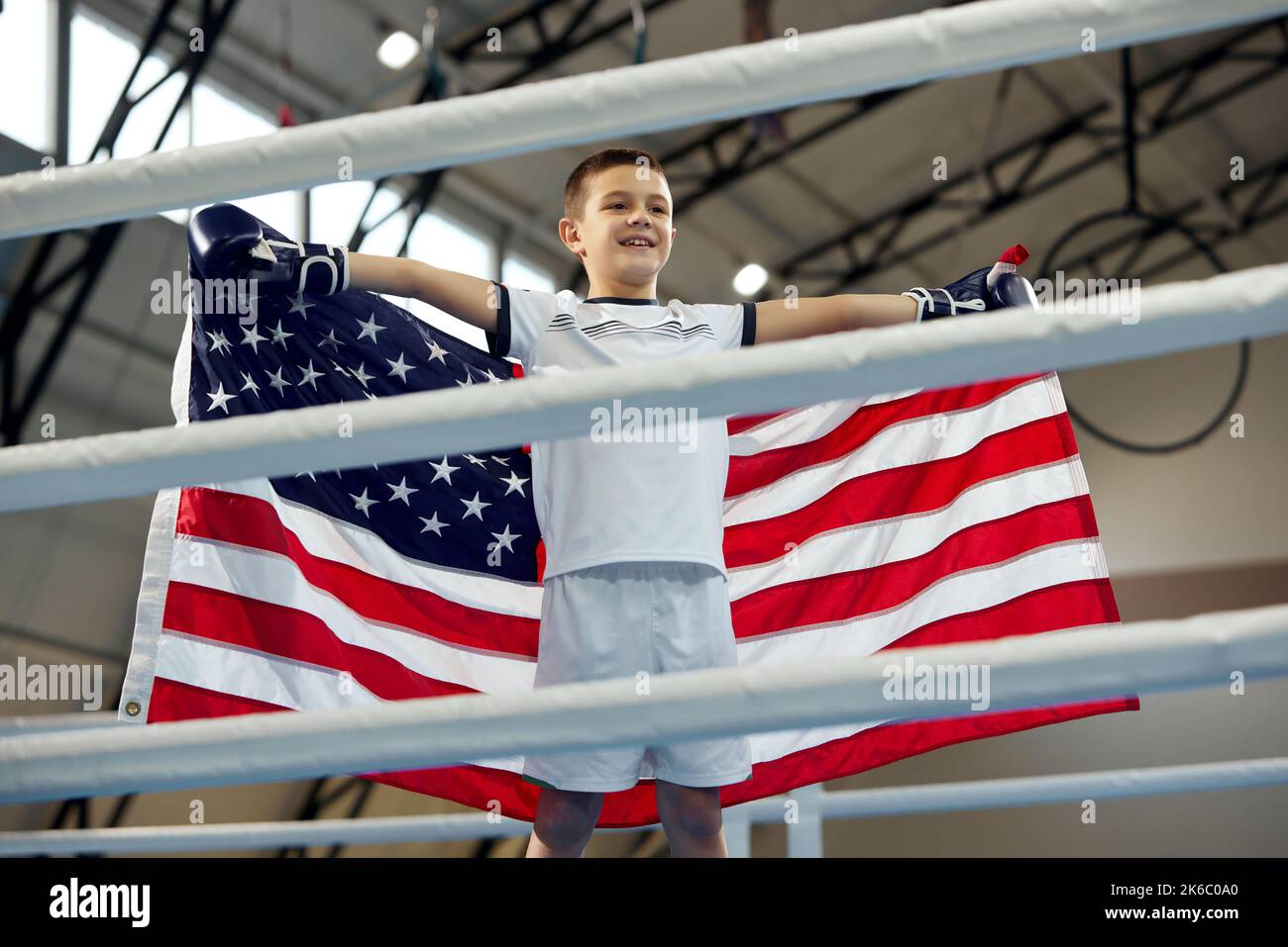 Winner emotions. Little boy, boxer with american flag on his shoulders