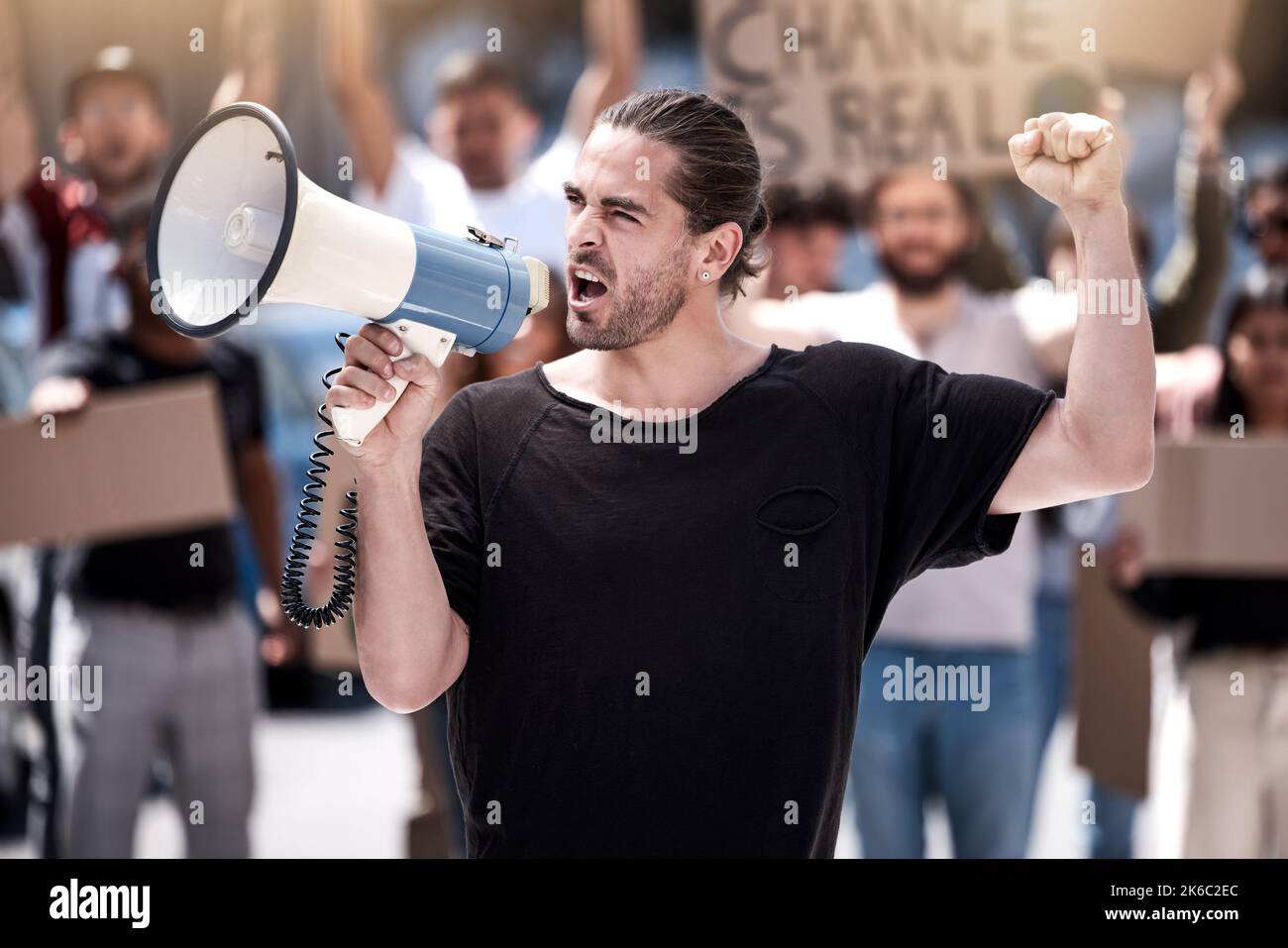 We wont back down. a young man yelling through a megaphone during a protest. Stock Photo