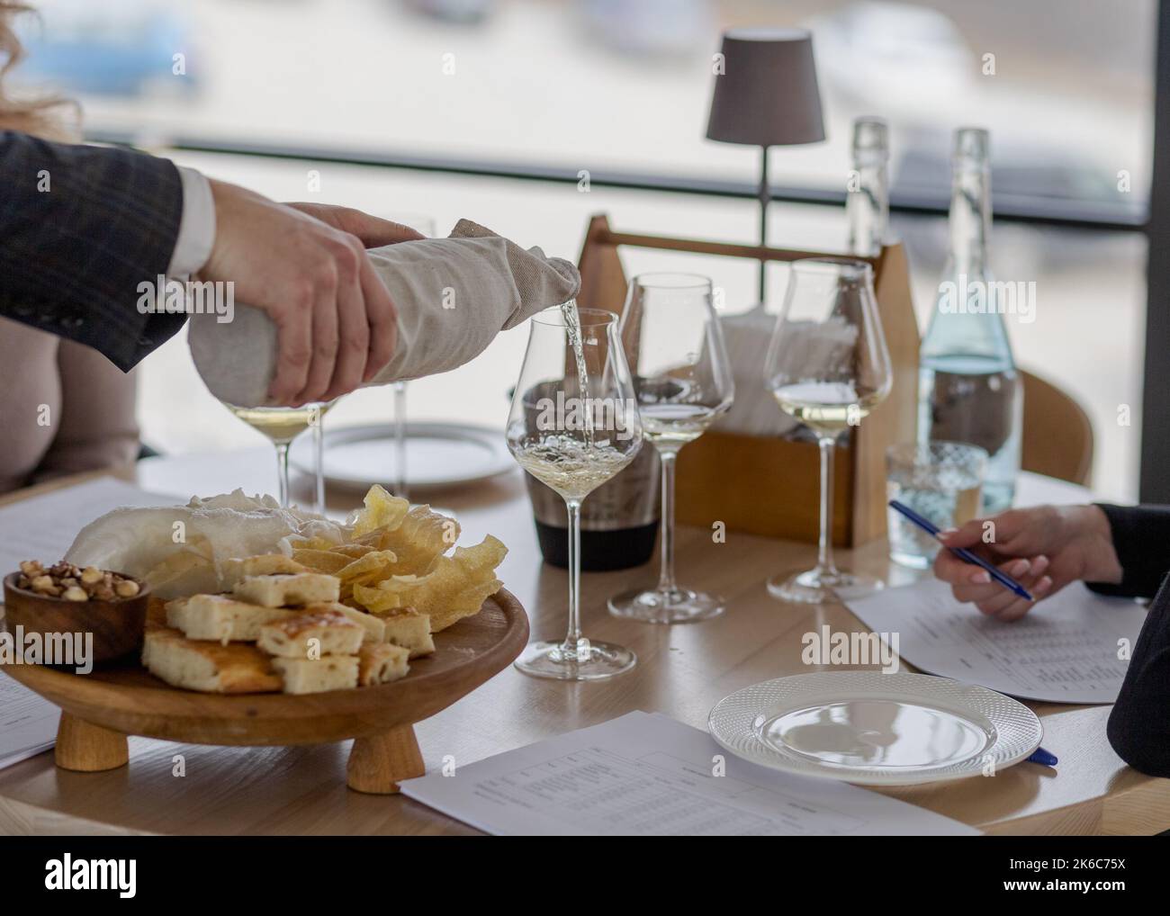 Sommelier pouring white wine into glasses with hidden bottle Stock Photo Alamy