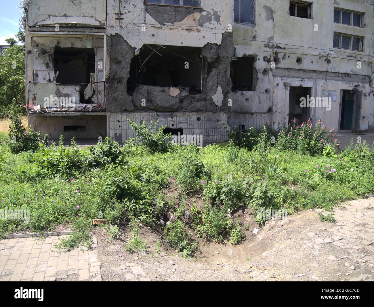 A destroyed ground floor apartment behind the impact crater of an artillery shell in Okhtyrka, Sumy Oblast, Ukraine Stock Photo