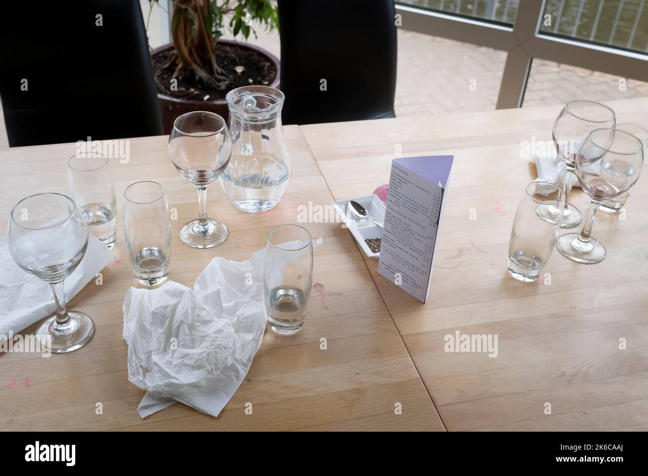 Various used serviettes napkins glasses and jugs left on a table in a restaurant cafe in Newquay in Cornwall in the UK. Stock Photo