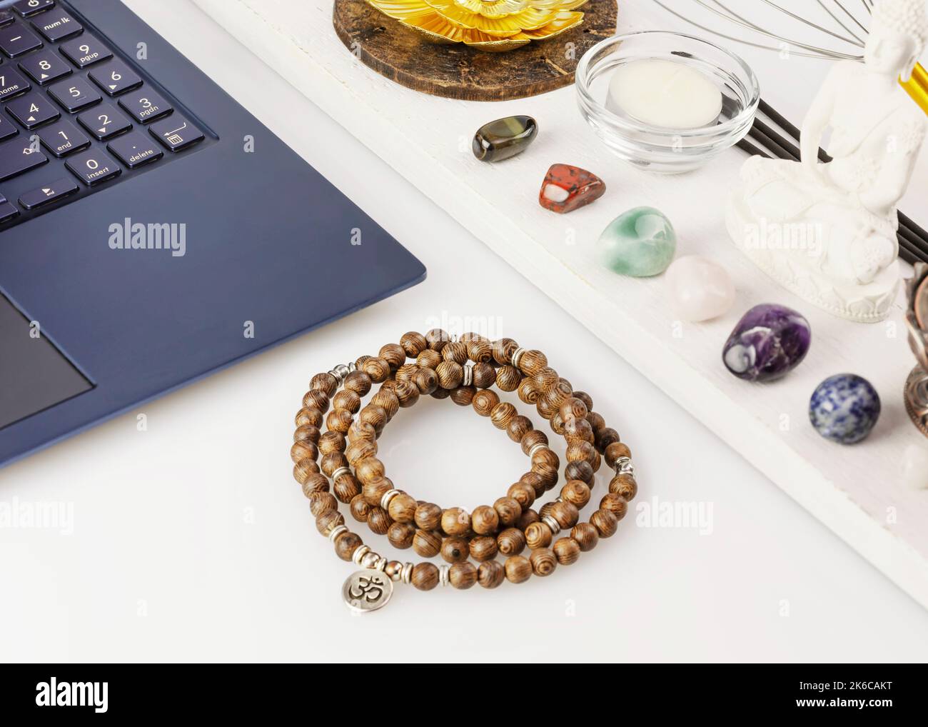 Laptop, rosary beads, chakra stones, aroma sticks, candle on work table Stock Photo