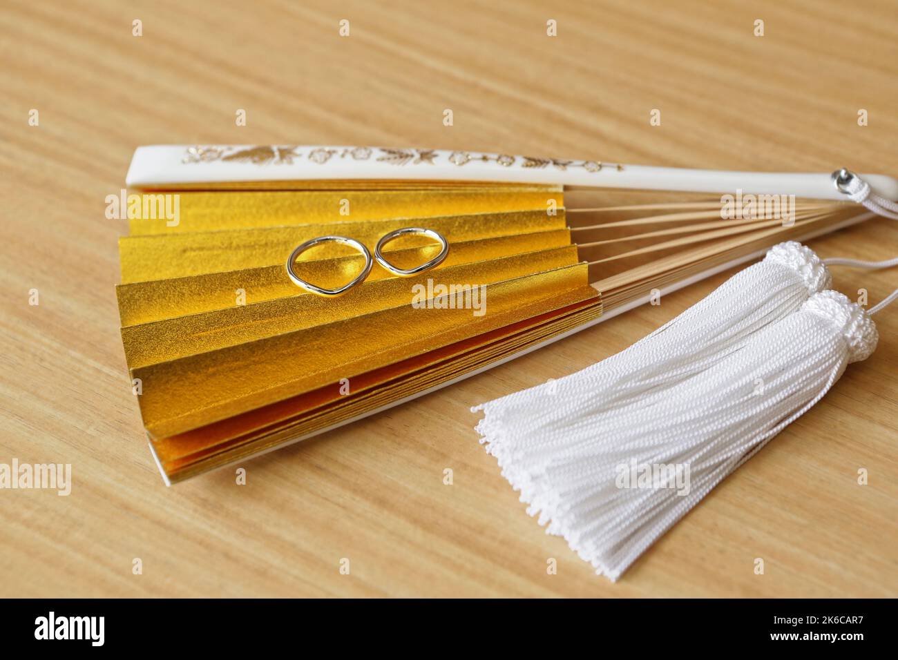 Japanese wedding rings on a gold folding fan with white tassel Stock