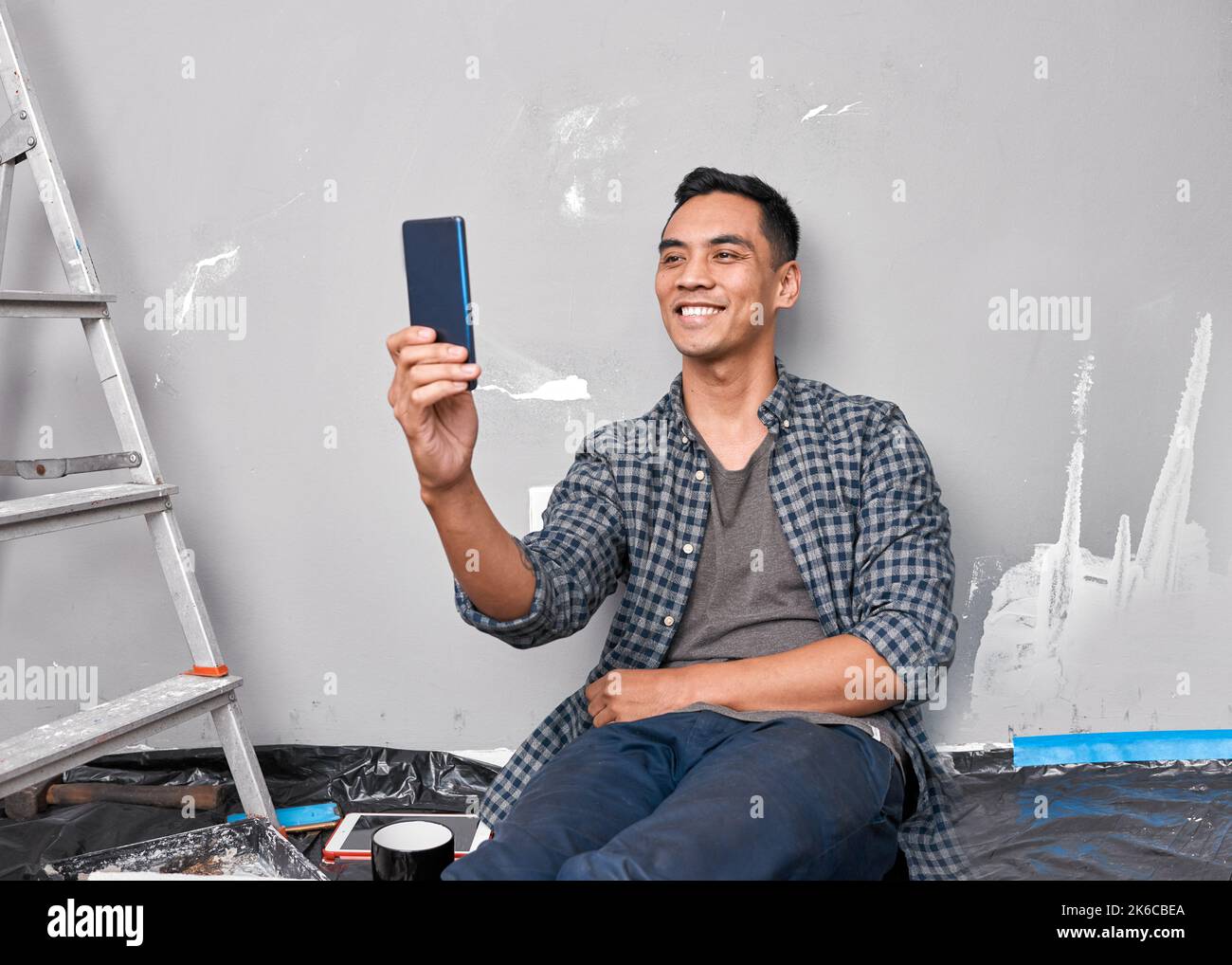 A young Asian man takes a selfie while busy with home improvement DIY project Stock Photo