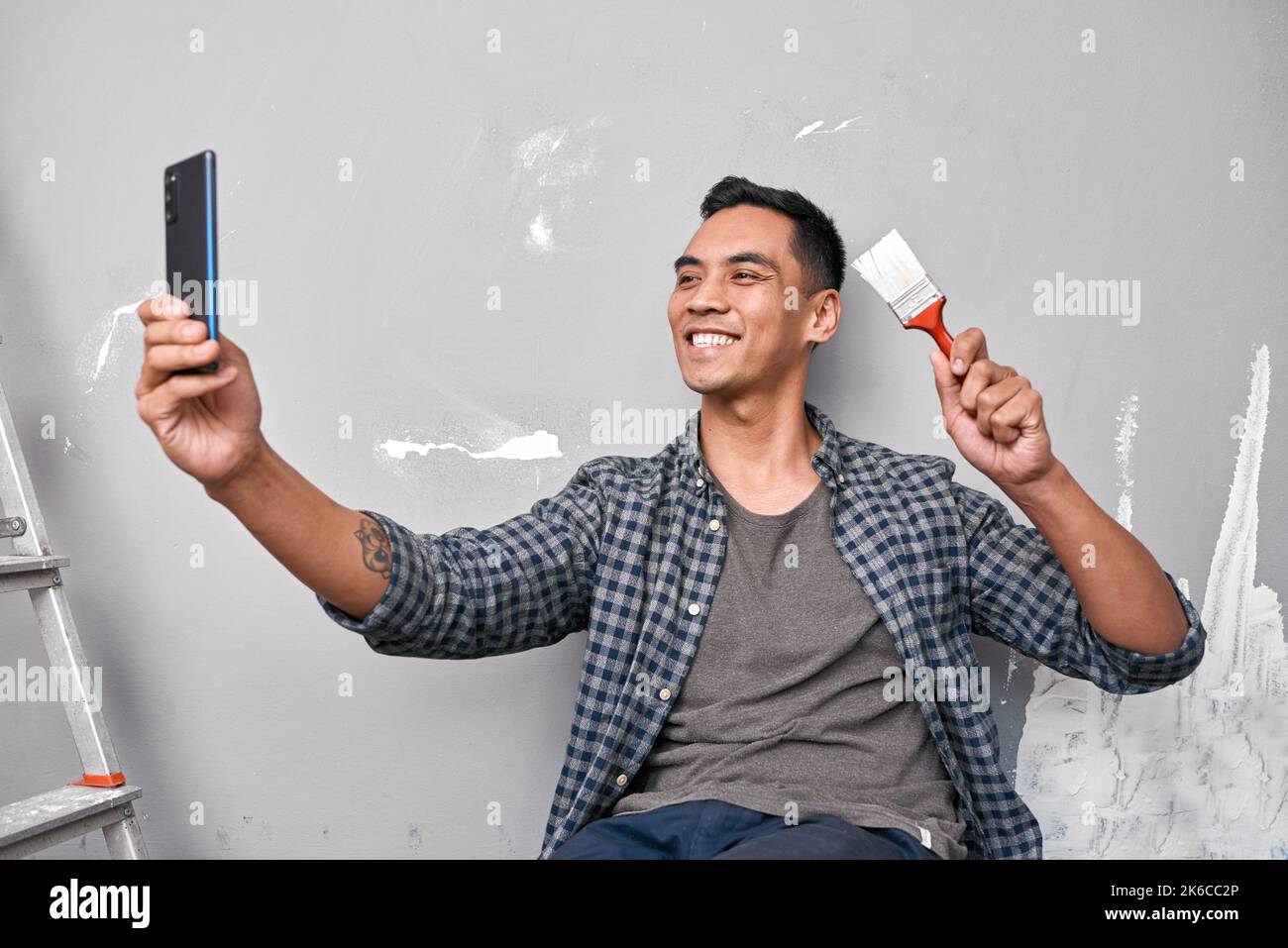 A young Asian man takes a selfie while busy with home improvement DIY project Stock Photo