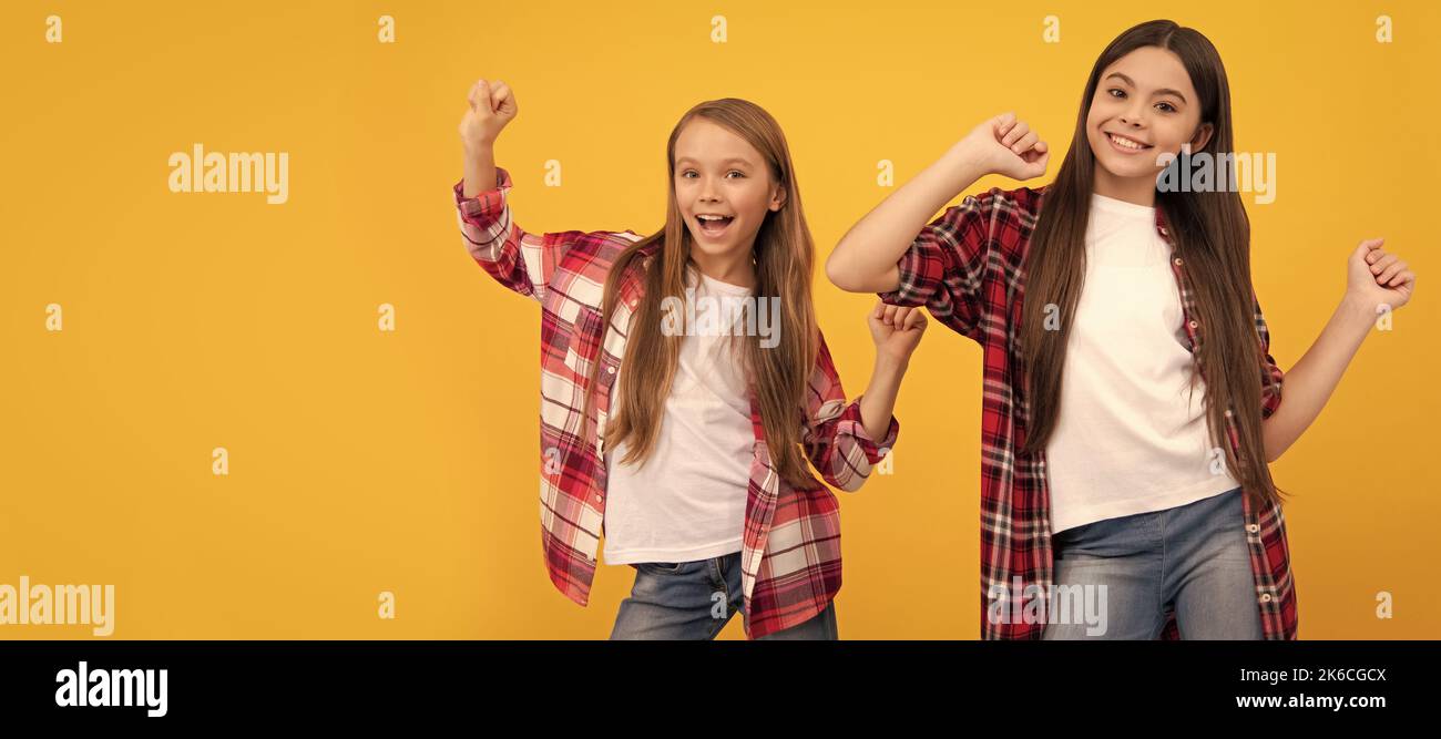 Girl friends. happy kids in casual checkered shirt having fun on yellow background, friendship. Casual teen children friends horizontal poster. Banner Stock Photo