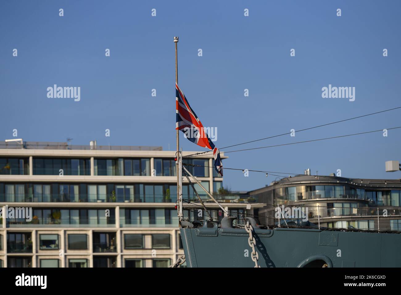 The flag on historic navy battle ship HMS Belfast moored in London on the River Thames  fly at Half Mast as a tribute to the late Queen Elizabeth 2nd. Stock Photo