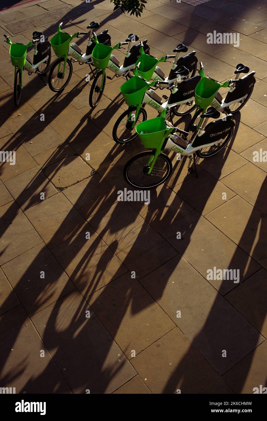 Atmospheric shot at sunset with low shadows shot from above of a group of  Lime electric rental cycles parked at Duke street Hill London UK. Stock Photo