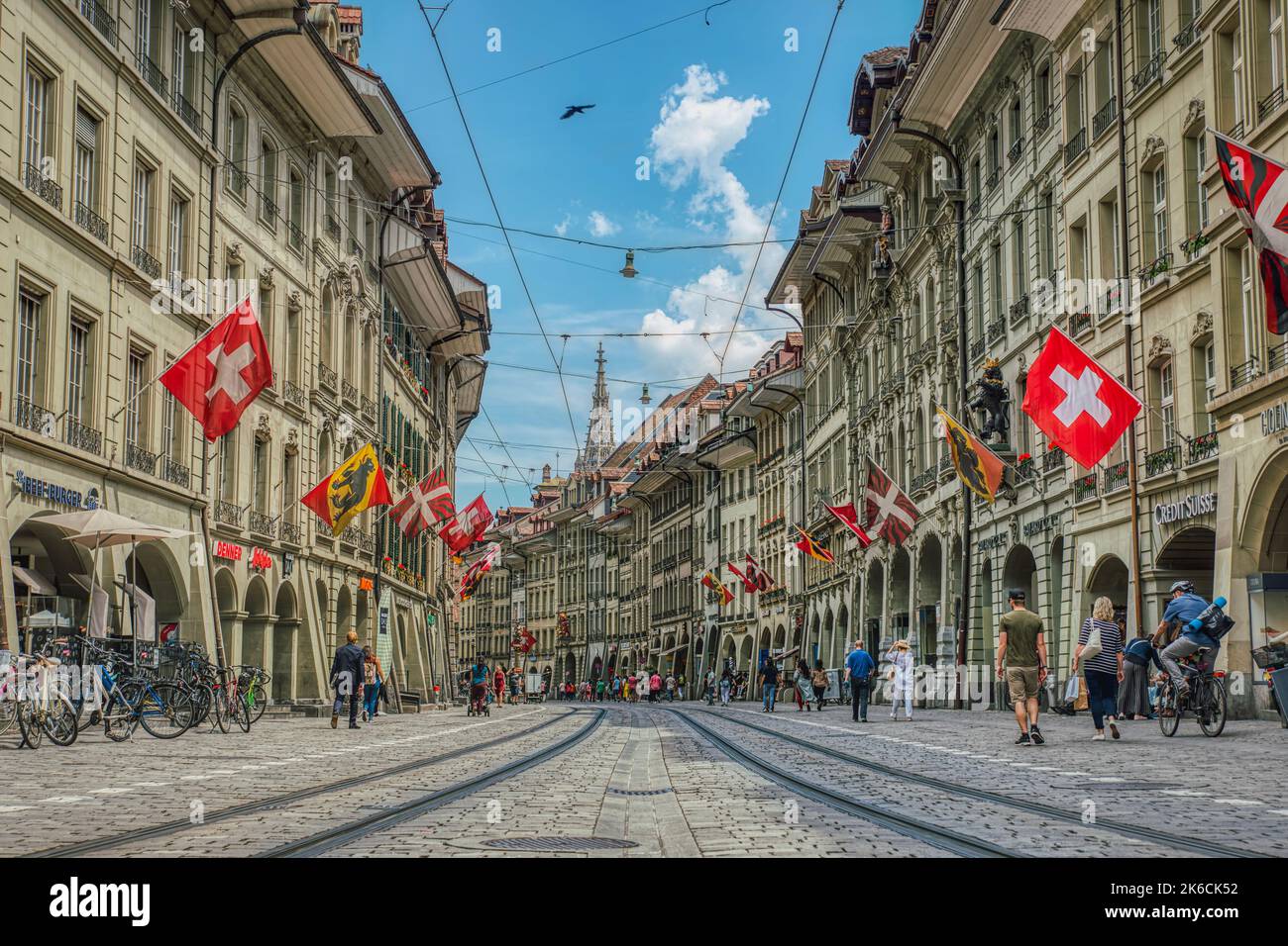 Marktgasse low view on tram tracks between Swiss historical houses or buildings with fluttering flags. Cablecar railway in Bern historical district Stock Photo