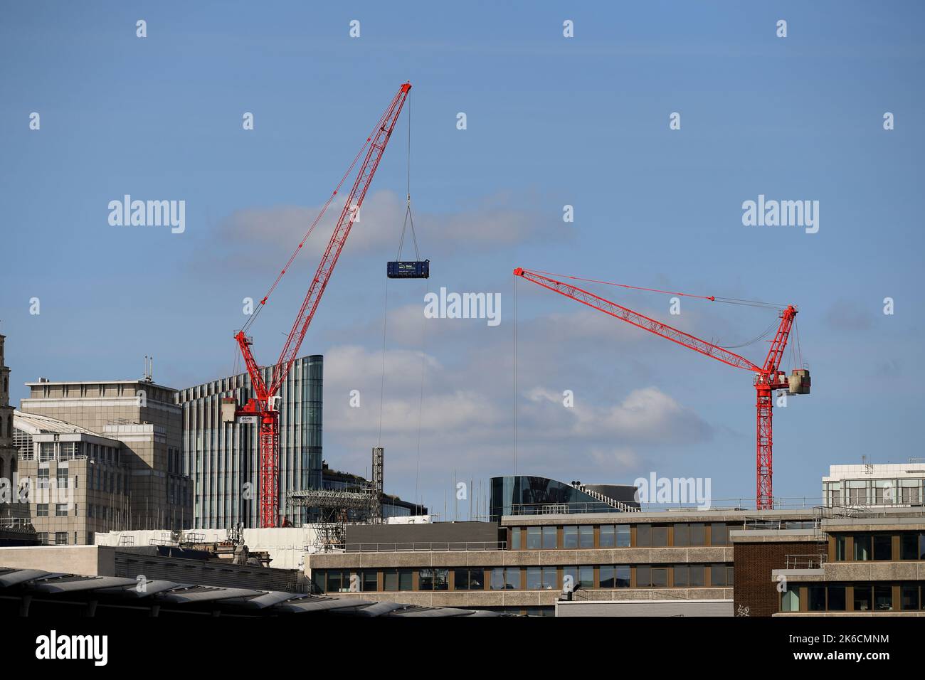 Cranes working in the London Skyline moving EMR metal recycling container from construction site. Stock Photo