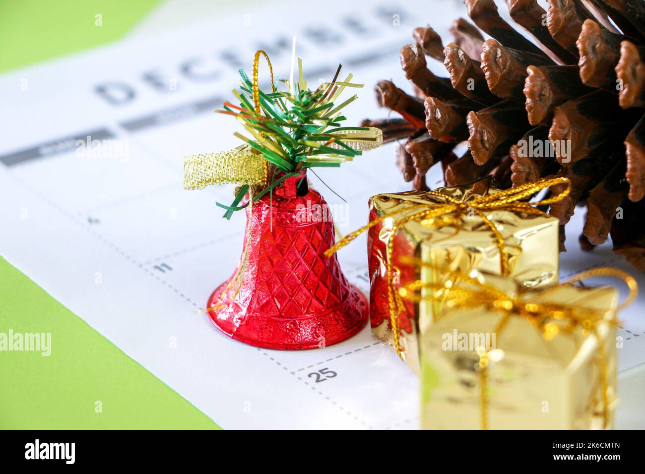 25th December Christmas day on Calendar surrounded by festive decor, pine cone, a shiny red bell, and two gold wrapped presents, Christmas concept Stock Photo