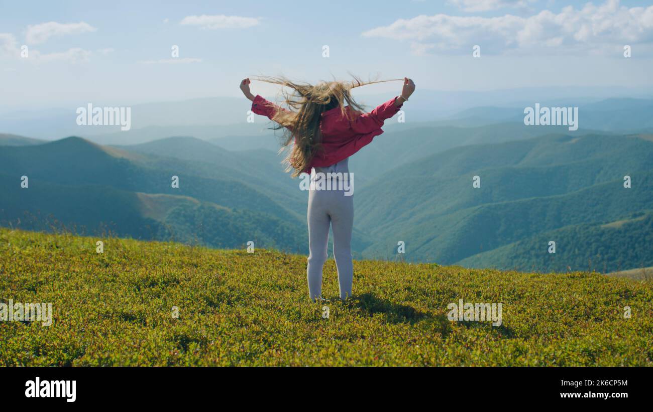 Young girl moves long hair, spinning around itself on beautiful