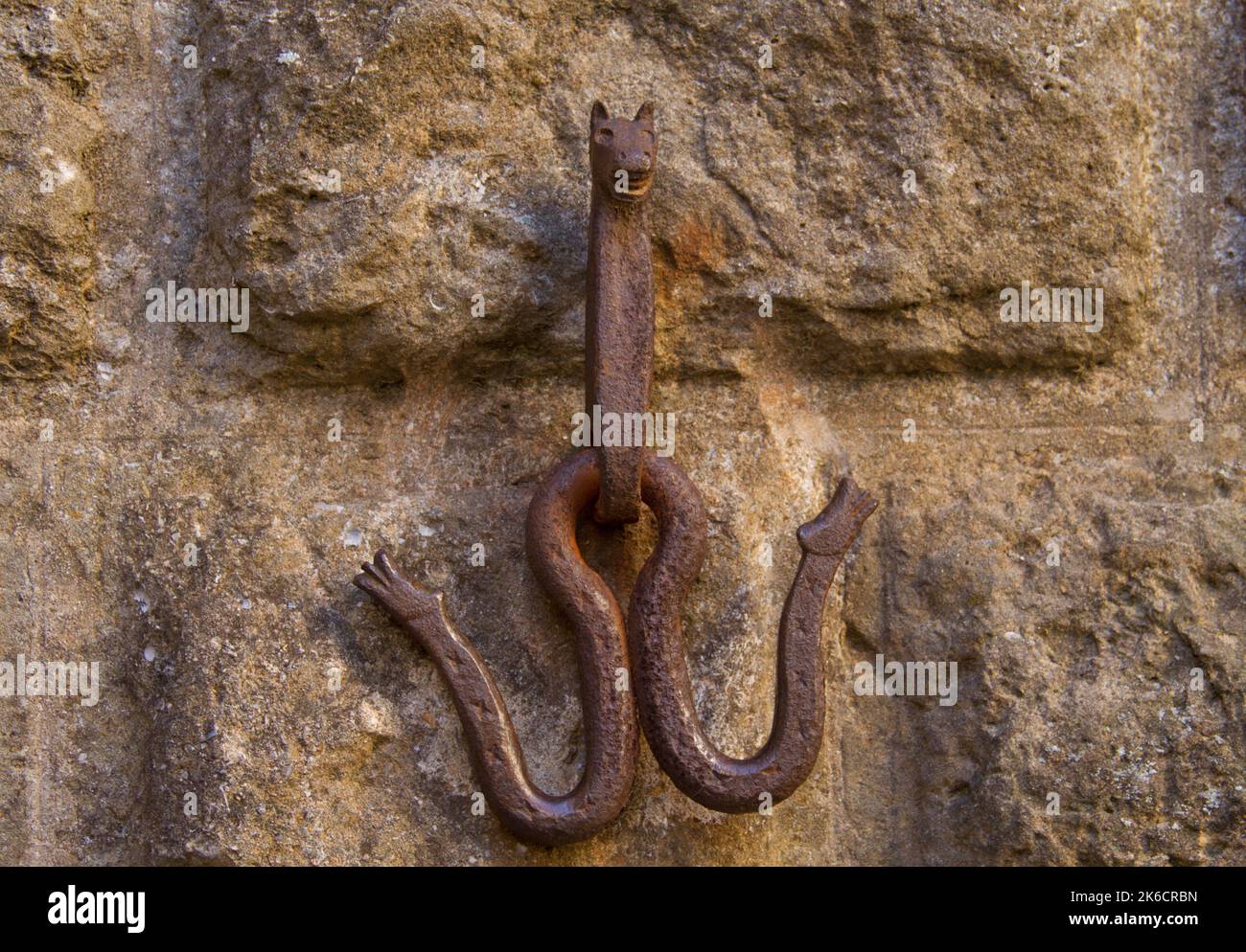 Rusted horse hitching hook on an old stone wall shaped in the shape of a horse Stock Photo