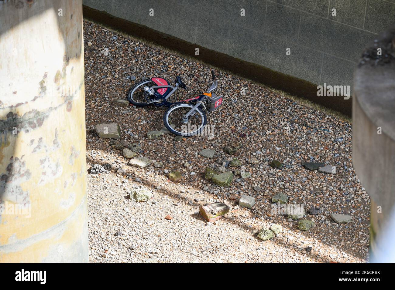 A Santander rental hire  bike ( Boris Bike ) lies dumped on the bank of the river Thames seen while the tide is out at South Bank London UK. Stock Photo