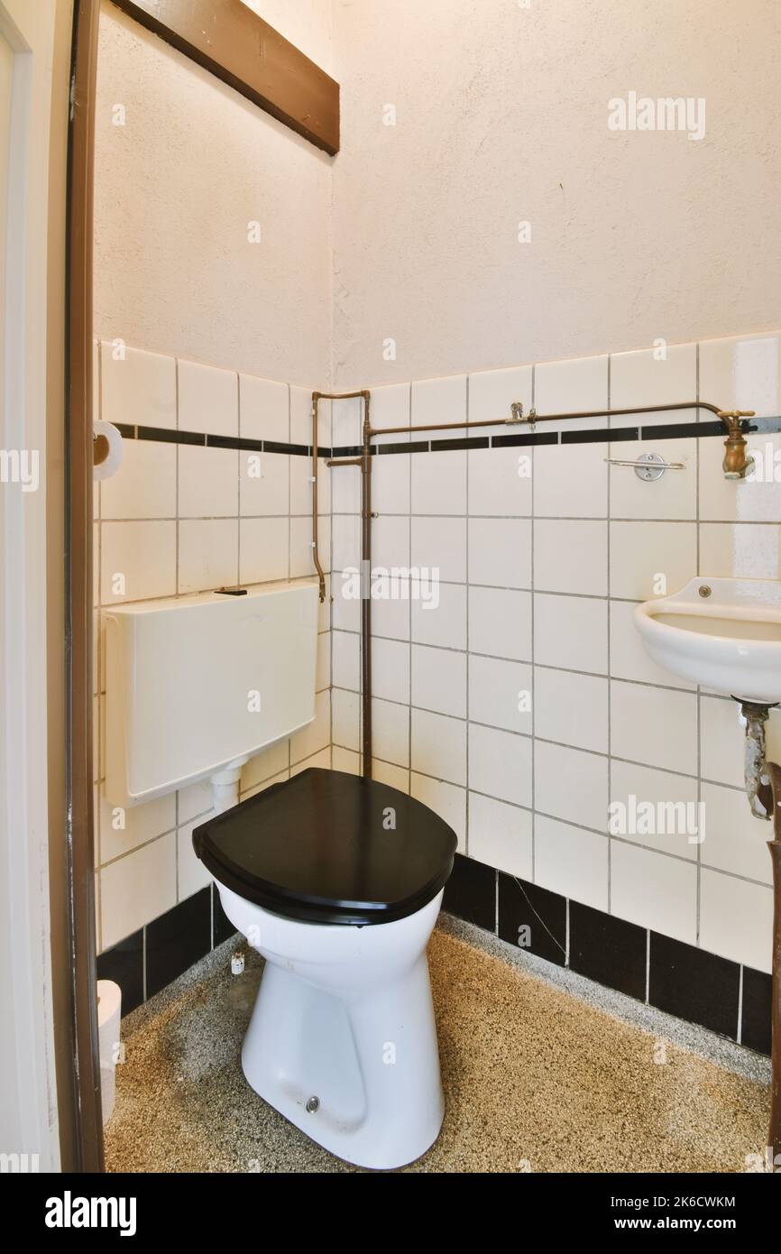 Wall hung toilet and small sink in corner in lavatory room with beige