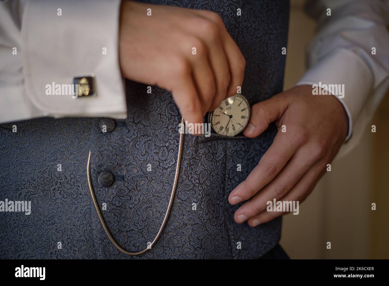 The hands of a man in an elegant suit holding a vintage stye fob watch Stock Photo