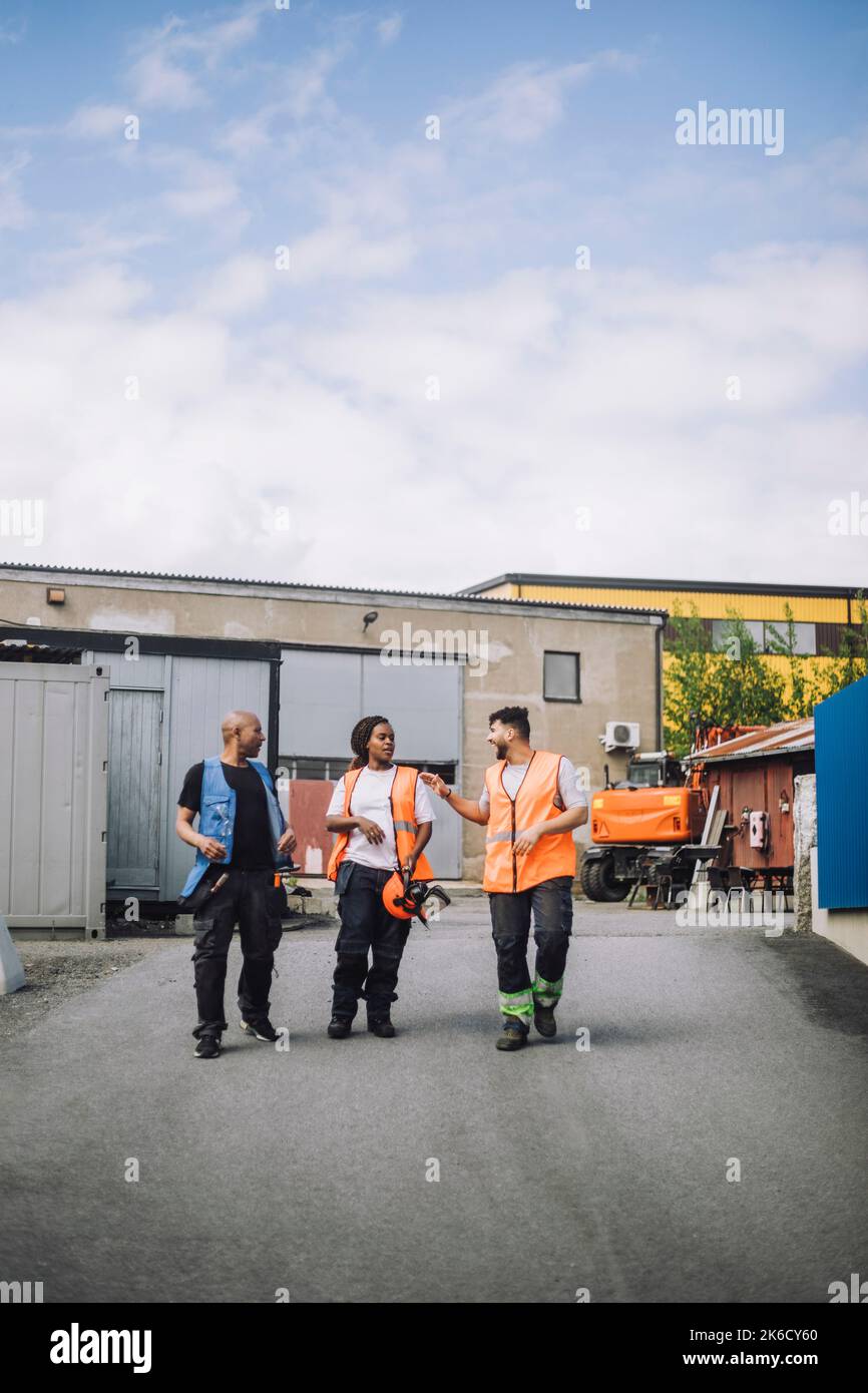 Full length of male and female construction workers walking together on road Stock Photo