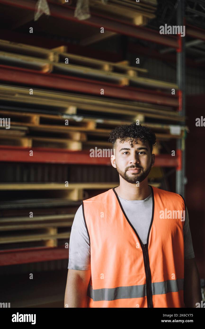 Portrait of confident young carpenter in reflective clothing at workshop Stock Photo
