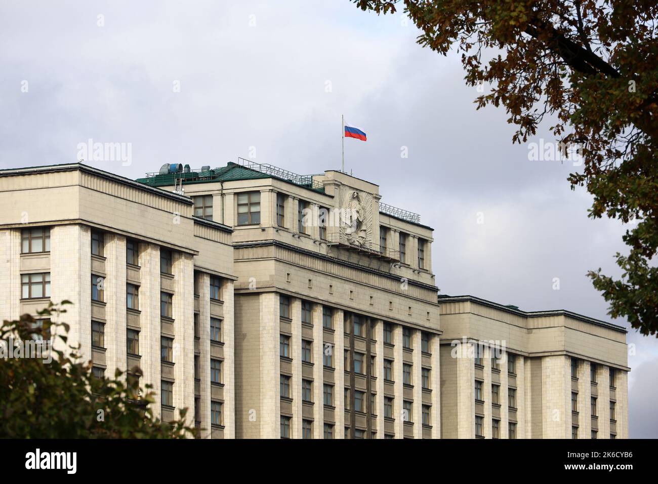 Parliament building with Russian flag in Moscow. The State Duma facade, view through the branches of autumn trees Stock Photo