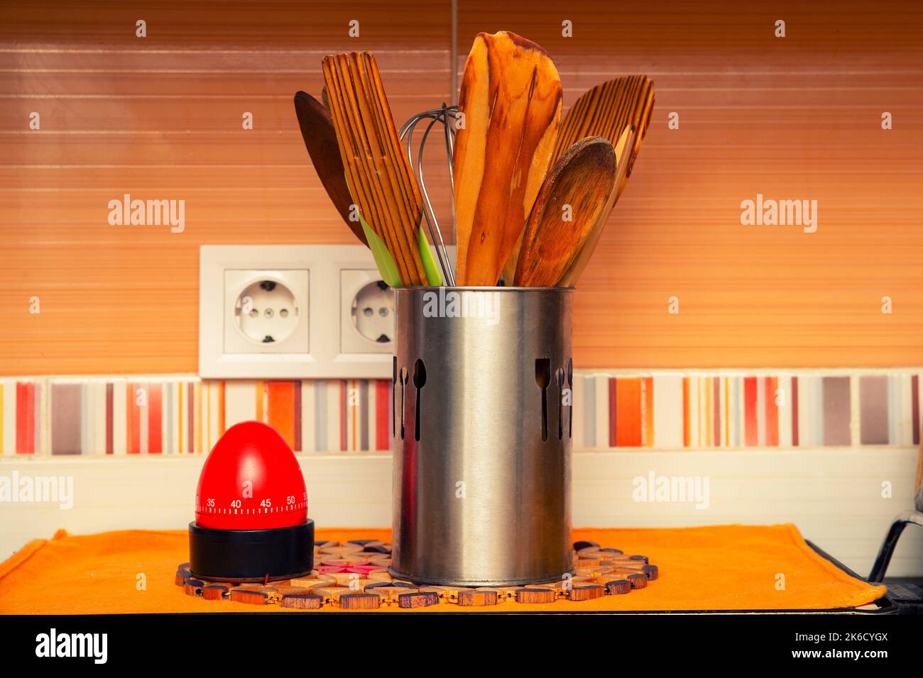 wooden cooking utensils in a metal container next to a timer Stock