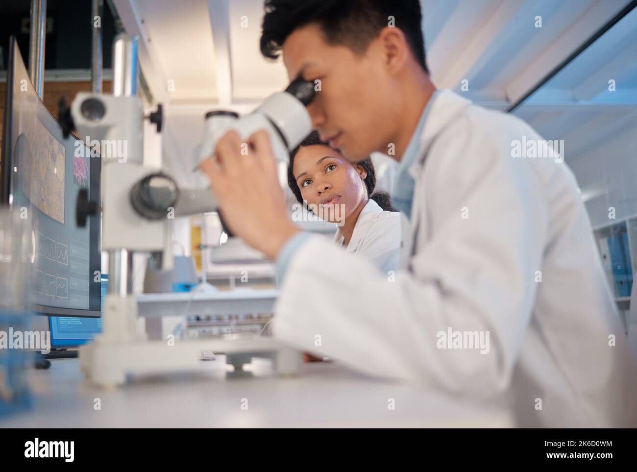 Waiting with baited breath. a young male lab tech analysing samples through a microscope. Stock Photo