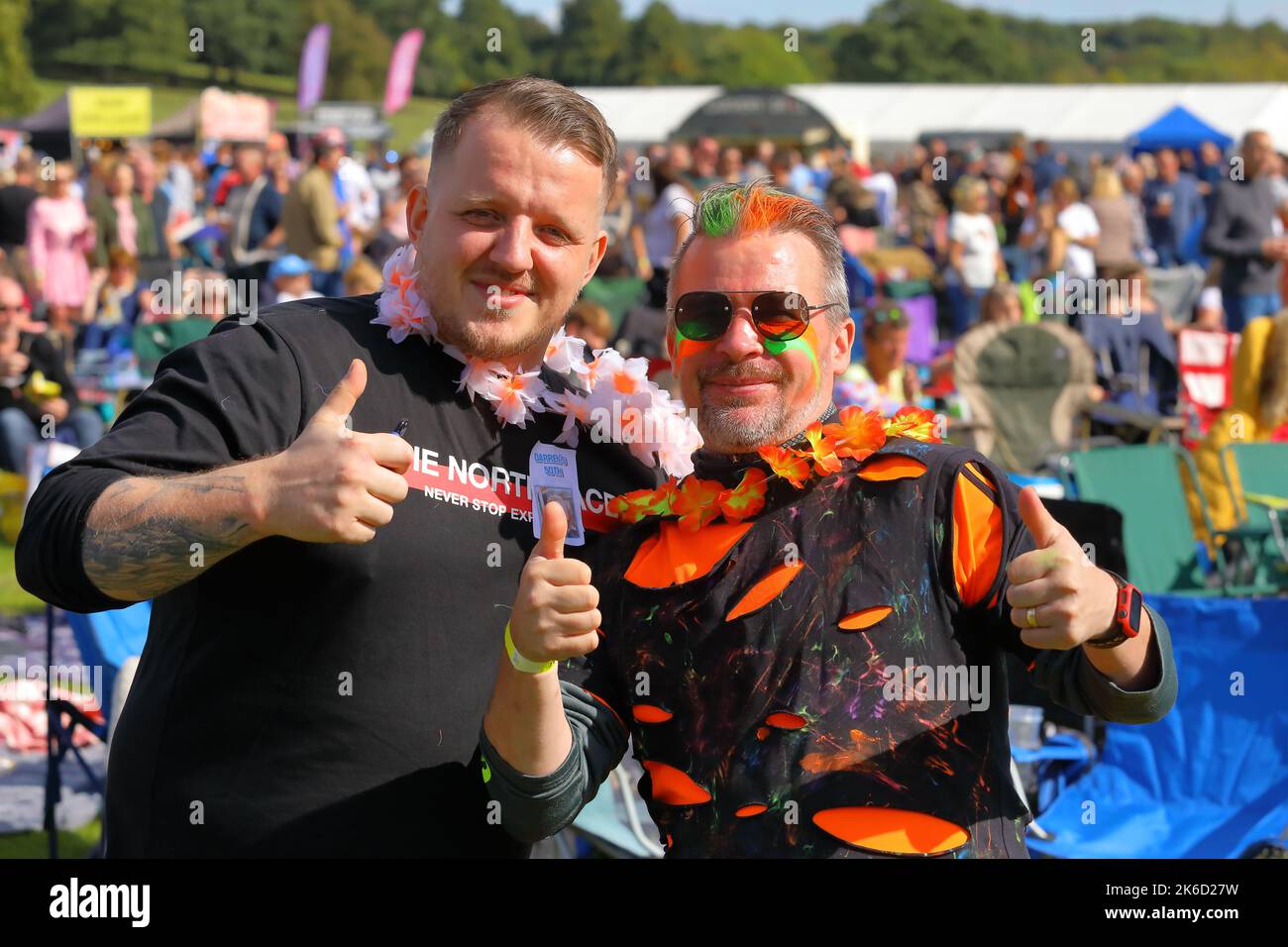 Two men posing for a photo at wentworth woodhouse festival 2022 one with green and orange hair and face paint,giving a thumbs up Stock Photo