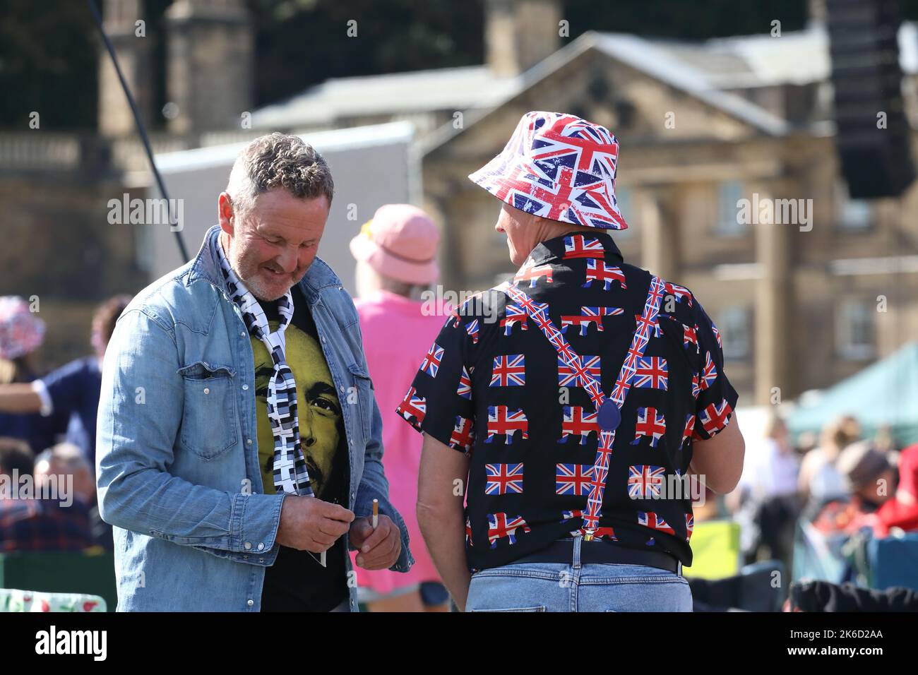two men talking  at wentworth woodhouse festival 2022 one dressed with aunion jack shirt braces and a floppy hat Stock Photo