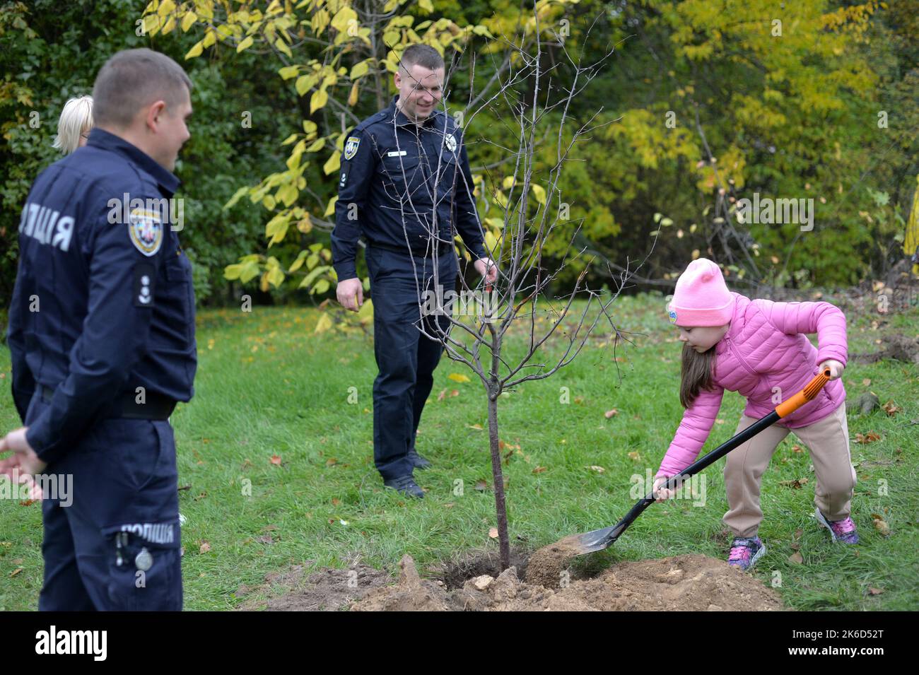 KYIV, UKRAINE - OCTOBER 11, 2022 - Policemen and a girl take part in the All-Ukrainain planting of the Alley of Defenders of Ukraine in the National Botanical Garden of the National Academy of Sciences of Ukraine, Kyiv, capital of Ukraine. Stock Photo