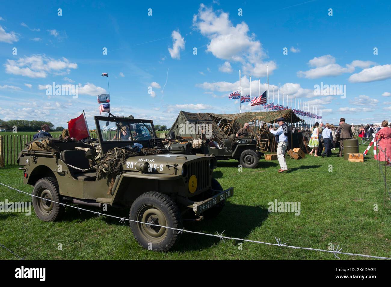 WW2 American Jeeps on display next to Union Jack and Stars and Stripes flags at half mast in respect of the Queen's death, BARC Revival, Goodwood, UK Stock Photo