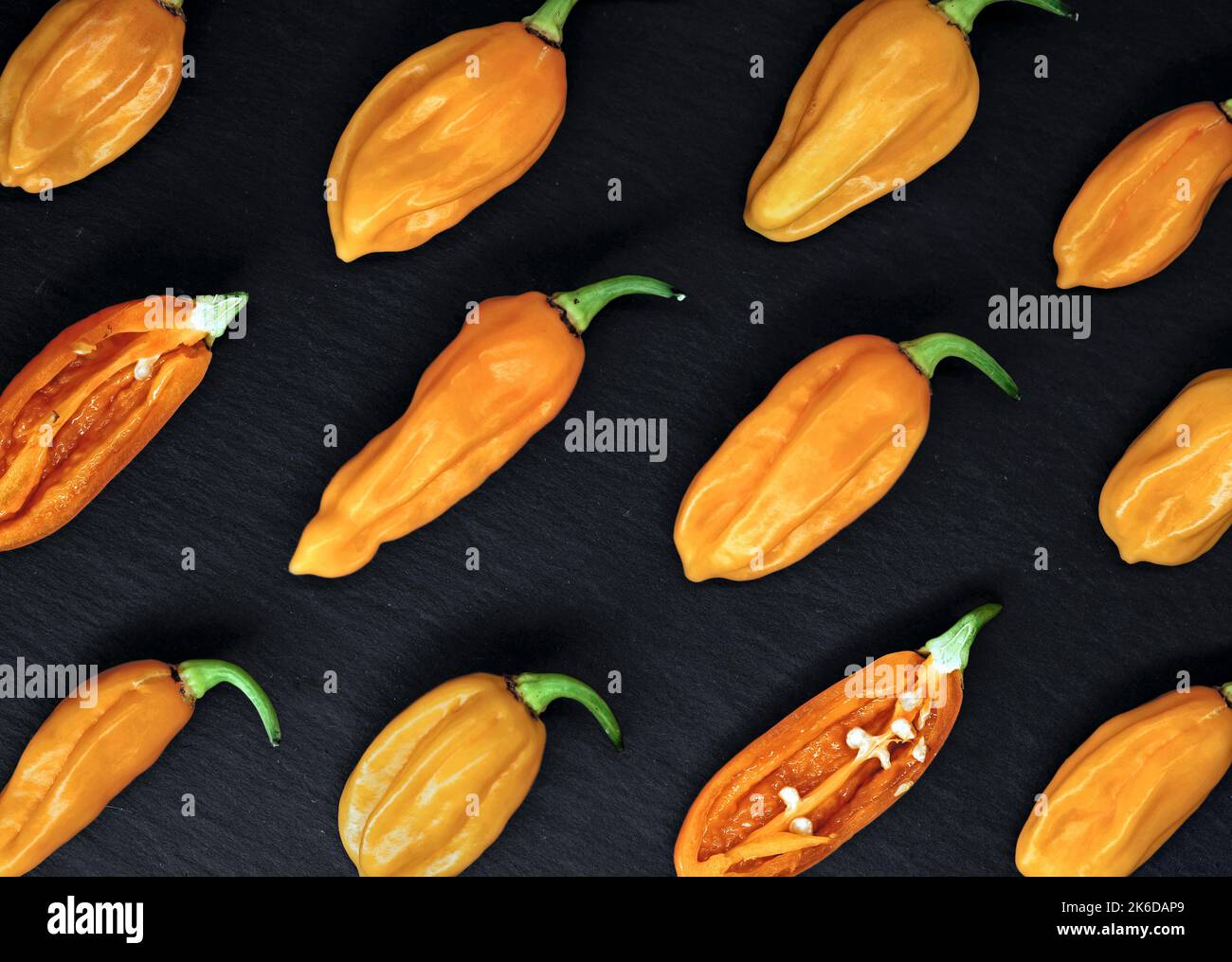 top view of hot orange chili peppers, bhut jolokia, on black slate background, diagonal arrangement of the hottest chillies in the world Stock Photo