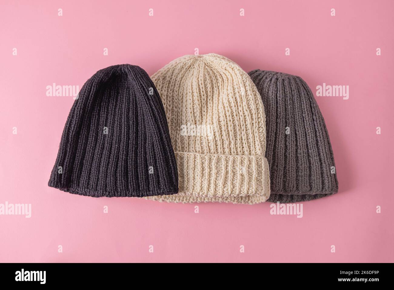 Top view of wool knitted hats on soft pink background. Handmade knitted clothes, winter close concept Stock Photo